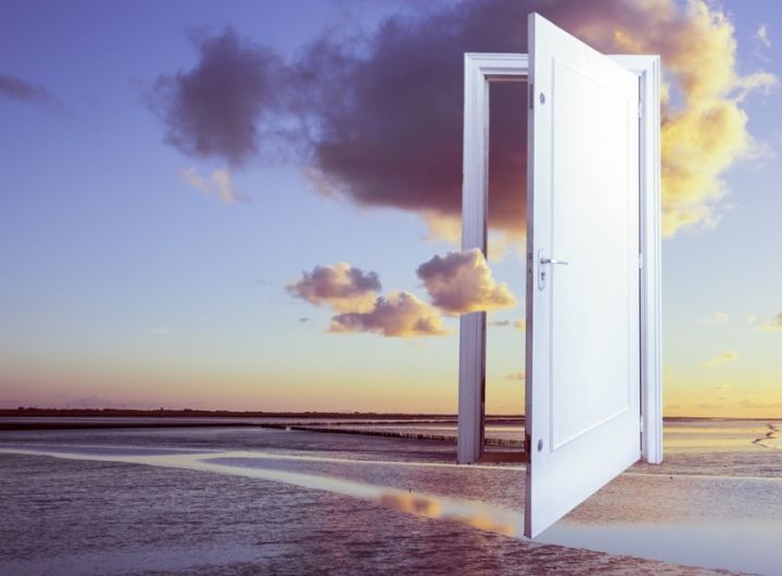 surreal image of floating door over the ocean at sunset
